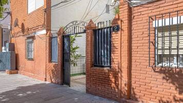 Un edificio de ladrillo con entrada protegida por una reja, numerado 2, y una antena parabólica en el techo.