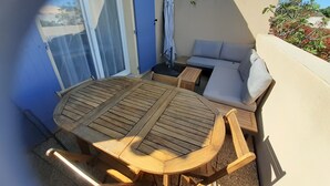 A sunlit patio with a round wooden table and chairs, a sofa, and a sliding glass door. - Under the Alpilles sun  (Mouriès)