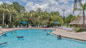 A swimming pool with lounge chairs and umbrellas, surrounded by palm trees and a thatched-roof structure. - COMFORTABLE APARTMENT - A REAL VACATION SPOT. HAS EVERYTHING YOU NEED-POOLS-LAKE (Davenport)