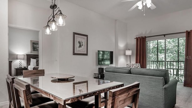 A dining area with a wooden table and chairs, a ceiling fan, and a sofa in the background. - COMFORTABLE APARTMENT - A REAL VACATION SPOT. HAS EVERYTHING YOU NEED-POOLS-LAKE (Davenport)