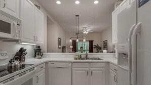 A modern kitchen with white cabinetry, a built-in microwave, a coffee maker, and a dishwasher. - COMFORTABLE APARTMENT - A REAL VACATION SPOT. HAS EVERYTHING YOU NEED-POOLS-LAKE (Davenport)