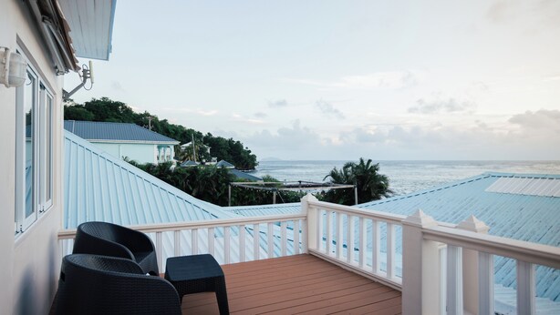 Un balcon donnant sur l’océan, agrémenté d’une balustrade et de deux chaises.