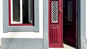 A building facade with a red door and a window with a lattice design.