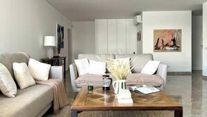 Ein modernes Wohnzimmer mit einer Sofagarnitur, einem Couchtisch und einem Gemälde an der Wand.