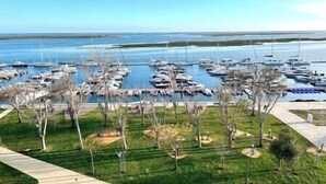 A marina with numerous boats docked, surrounded by a grassy area with trees. - Luz do Mar 1 - Olhão, Algarve (Olhão)