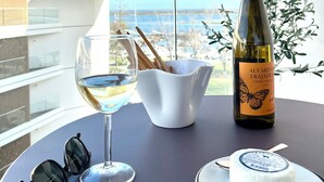 A table with a bottle of Alvarinho Trajadura wine, a glass of white wine, a bowl of crackers, and a plate with a white dessert. - Luz do Mar 1 - Olhão, Algarve (Olhão)