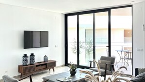 A modern living room with a flat-screen TV, a coffee table, and seating. - Luz do Mar 1 - Olhão, Algarve (Olhão)