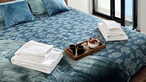 A hotel room with a bed, a view of the outside, and a tray with towels and a bowl of fruit. - Luz do Mar 1 - Olhão, Algarve (Olhão)