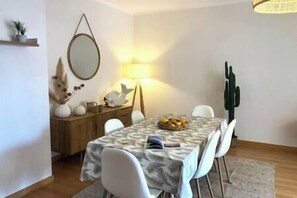 A dining area with a table set for four, a lamp, and a decorative wall piece.