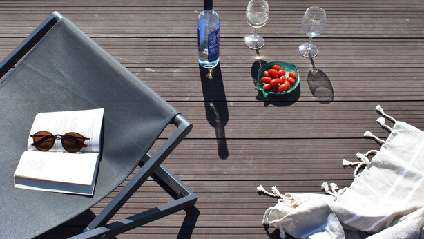 A poolside area with a lounge chair, a bottle, glasses, and a bowl of fruit. - Luz Marina - Olhão, Algarve (Olhão)