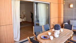 A modern dining area with a wooden table, chairs, and a potted plant. - Luz Marina - Olhão, Algarve (Olhão)
