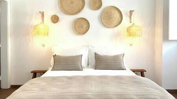 Un dormitorio con una cama, dos mesitas de noche y lámparas fijadas a la pared.