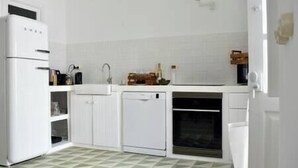 Una cocina con armarios blancos, lavavajillas, fregadero y estufa.