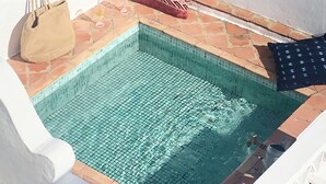 A small pool with tiled edges, a beige bag, and a patterned cushion on a white wall. - Casa Saudade - Olhão, Algarve (Olhão)