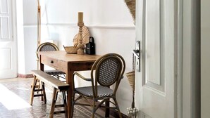 A dining area with a wooden table, two chairs, a bench, a lamp, and a basket. - Casa Saudade - Olhão, Algarve (Olhão)