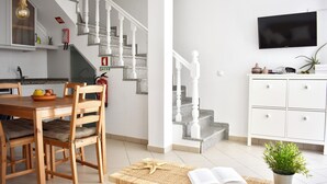 A modern kitchen with a dining area, a staircase, and a living room with a TV. - Luz Santana - Olhão, Algarve (Olhão)