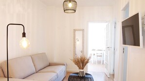 A modern living room with a sofa, a round coffee table, a floor lamp, and a TV mounted on the wall.