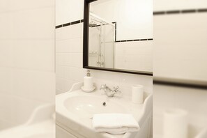 A bathroom with a white sink, a mirror, and a shower. - Luz Restauração - Olhão, Algarve (Olhão)