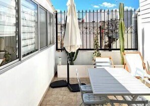 A patio with a table and chairs, a potted plant, and a metal fence. - Luz Restauração - Olhão, Algarve (Olhão)