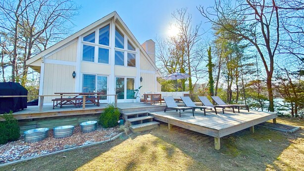 Ein modernes Haus mit Terrasse, Sitzgelegenheiten im Freien und einem Pool.