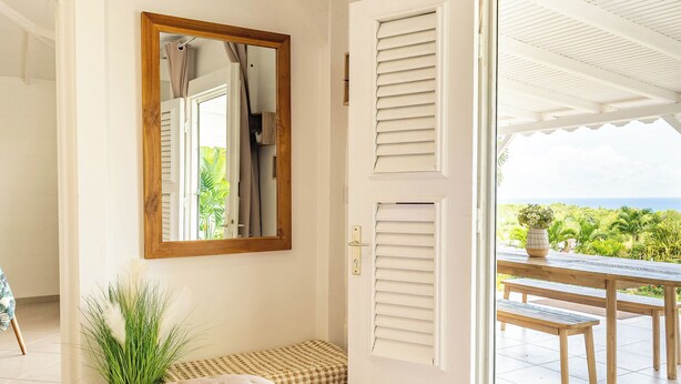 Une chambre à coucher avec un lit, un miroir, une fenêtre avec des volets et une vue sur l’extérieur.