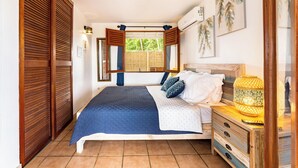 A bedroom with a bed, wooden wardrobe, and a nightstand with a lamp.