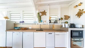 A compact kitchen with white appliances, a wooden countertop, and decorative wall art.