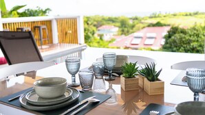 A dining table set with glassware and plates, a plant, and a view of a green landscape.