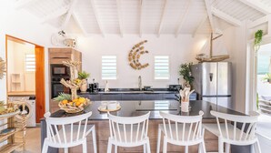 Una cocina moderna con una isla central, taburetes blancos y una luna decorativa grande en la pared.
