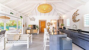 Una cocina amplia con una isla central, muebles blancos y un techo alto con vigas a la vista.