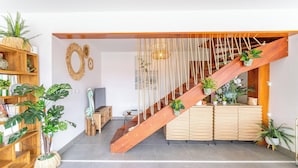 Un interior moderno con una escalera de madera, una estantería de madera y varias plantas en macetas.
