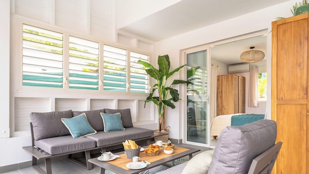Una sala de estar moderna con un sofá gris, una mesa de centro de madera y una planta grande.