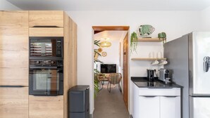 Una cocina moderna con armarios de madera, horno empotrado, refrigerador y un comedor con mesa y sillas.