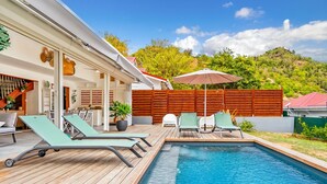 Una piscina con sillas de descanso y una terraza de madera.