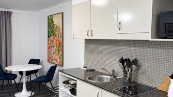 A compact kitchen with a sink, cabinets, and a dining area with chairs and a table.