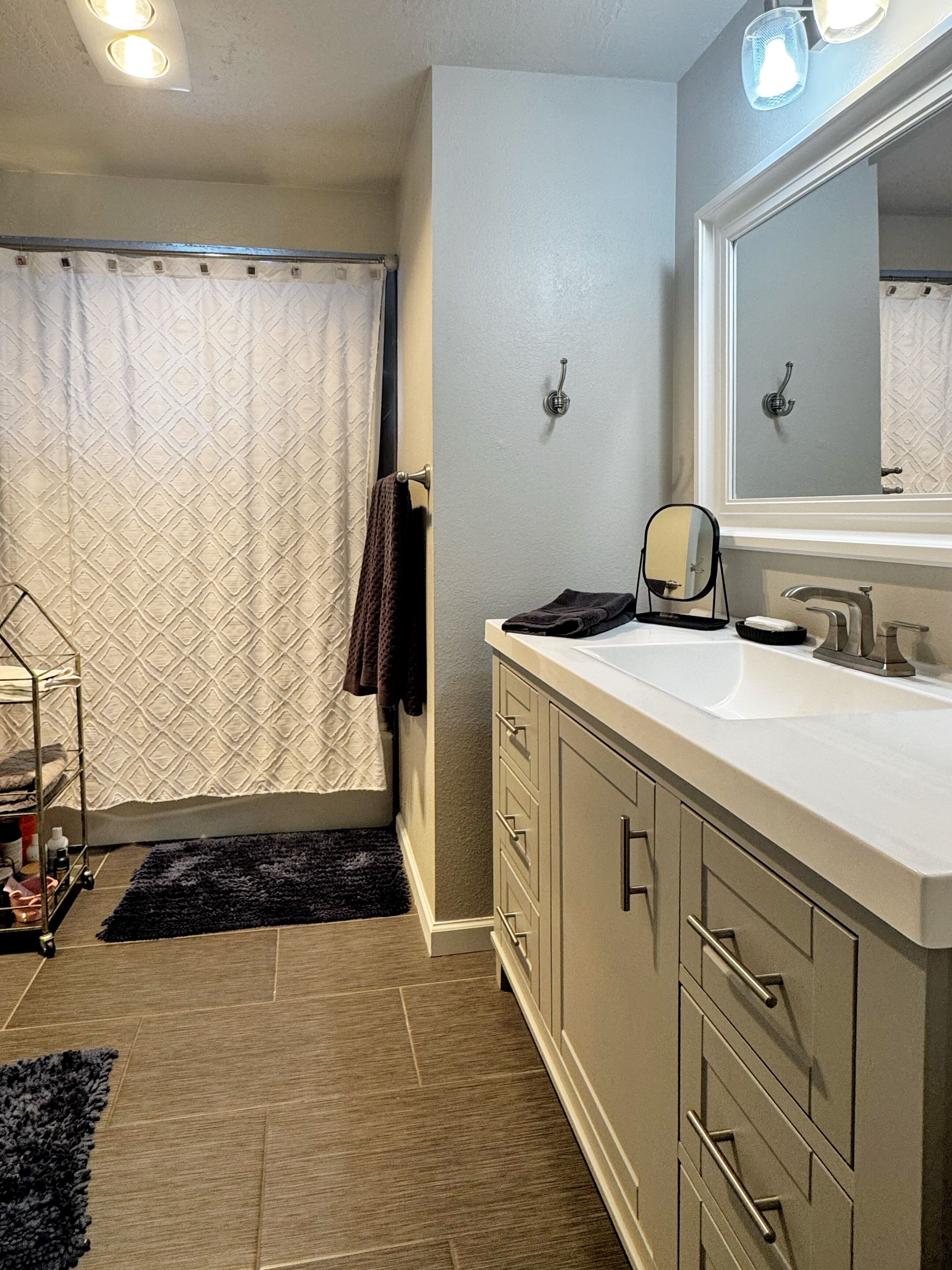 A bathroom with a large mirror, a sink, and a towel rack.