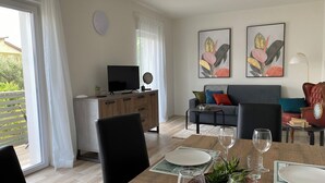 Een moderne woonkamer met een eethoek, een bank, een televisie en kunst aan de muur.