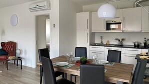 Een moderne keuken met witte kasten, een inbouwoven en een hanglamp.