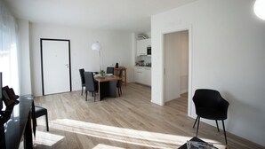 A modern apartment with a dining area, kitchen, and a living space.