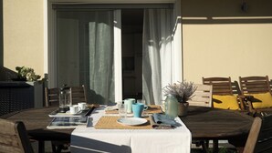 A dining table set for two with a white tablecloth, two chairs, a potted plant, and a menu.