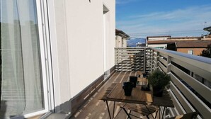 A balcony with a wooden table, chairs, and potted plants. - Eco Apartment View By Case al Lago (Peschiera del Garda)