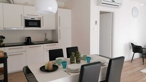 A modern kitchen with white cabinets, a black countertop, and a white ceiling light. - Eco Apartment View By Case al Lago (Peschiera del Garda)