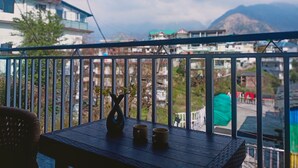 A balcony with a table, a vase, and a mug. - Check-in & Chill (Dharamshala)