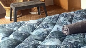 A bedroom with a bed, a television, two wicker chairs, a wooden wardrobe, and a ceiling fan. - Check-in & Chill (Dharamshala)
