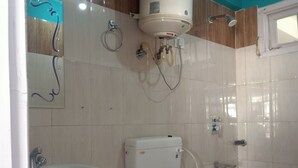 A bathroom with a toilet, sink, and a water heater mounted on the wall. - Check-in & Chill (Dharamshala)