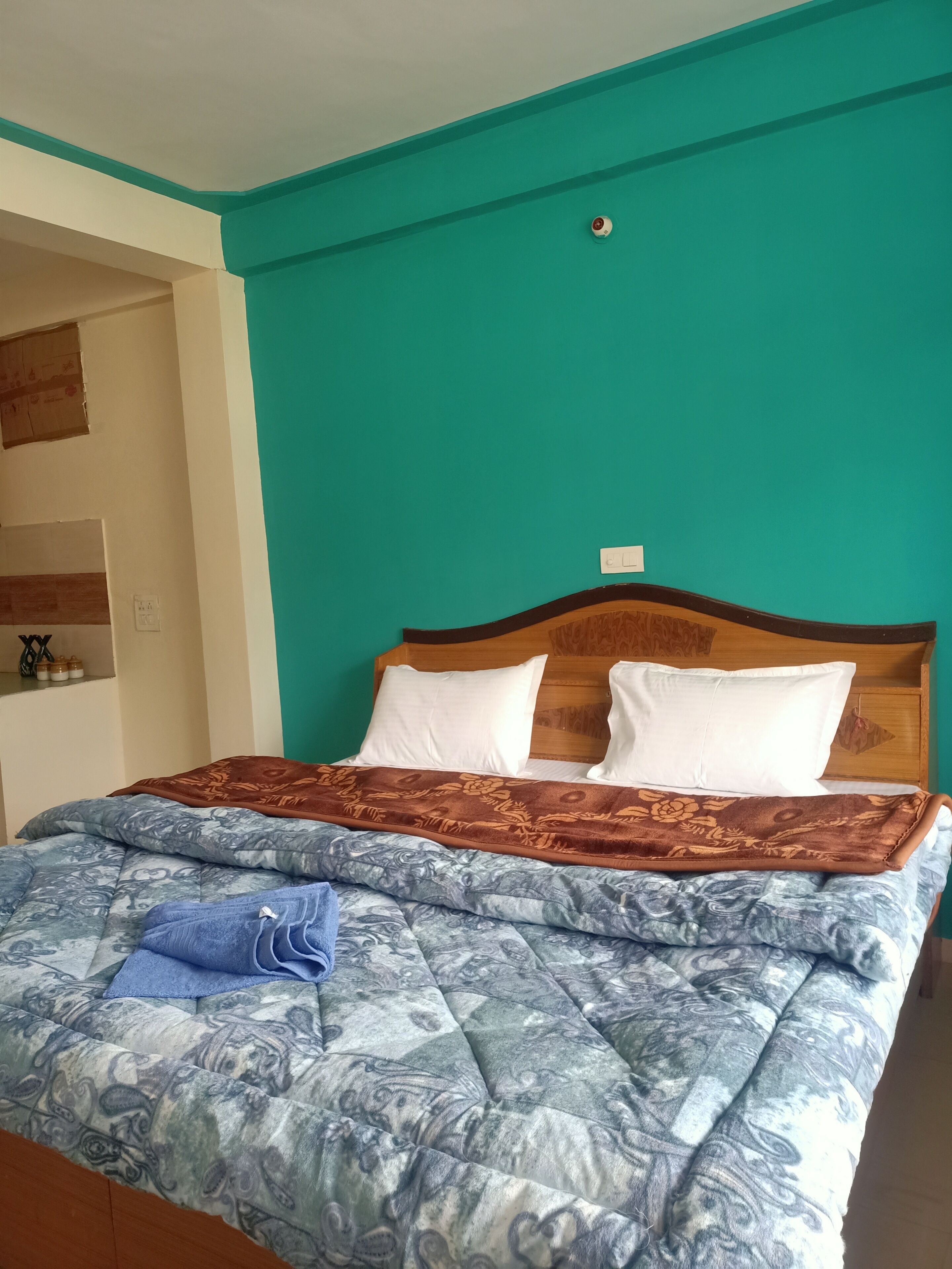 A bed with a patterned duvet, pillows, and a blue towel.