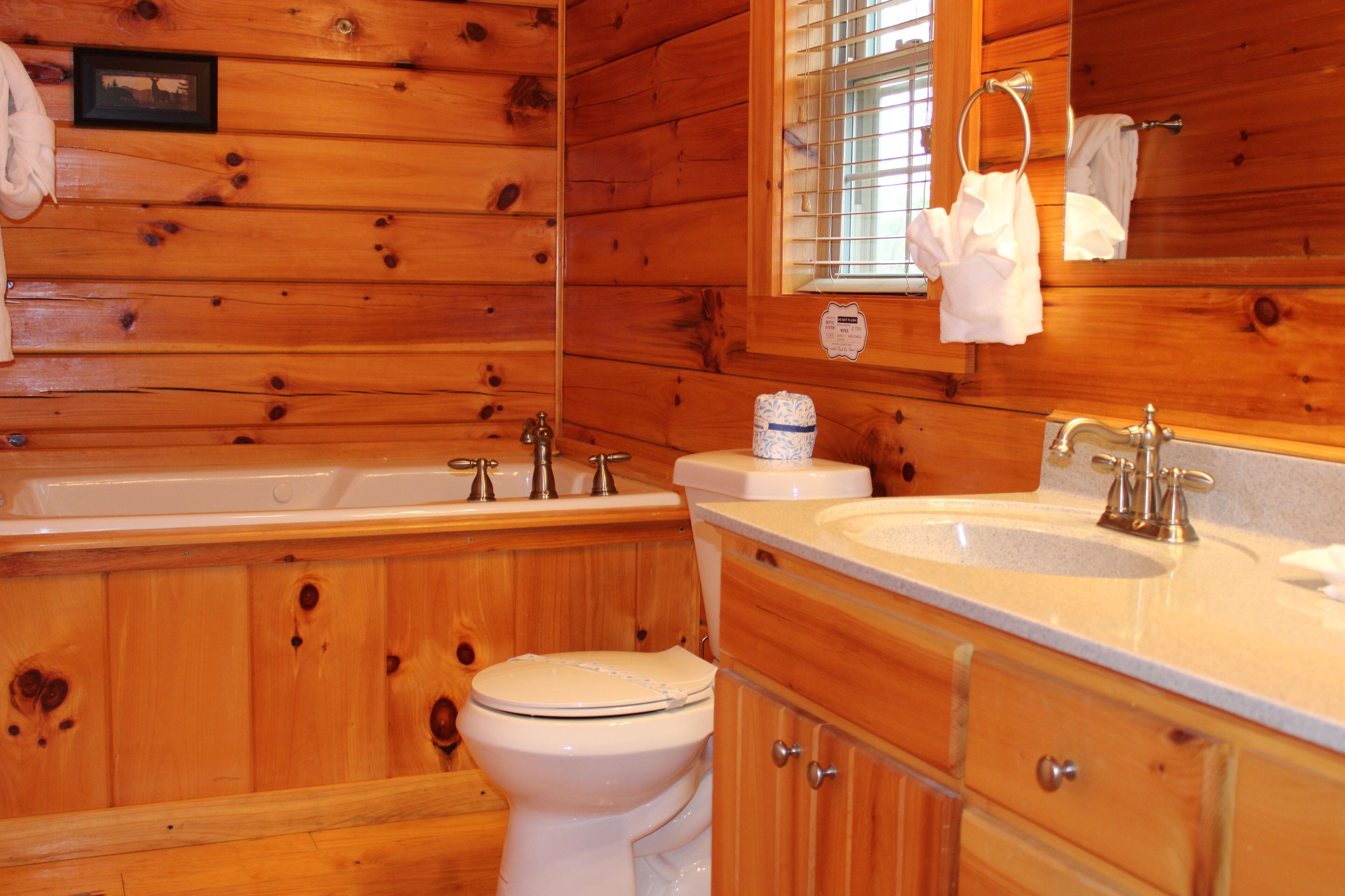 A wooden cabin bathroom with a toilet, sink, and bathtub.