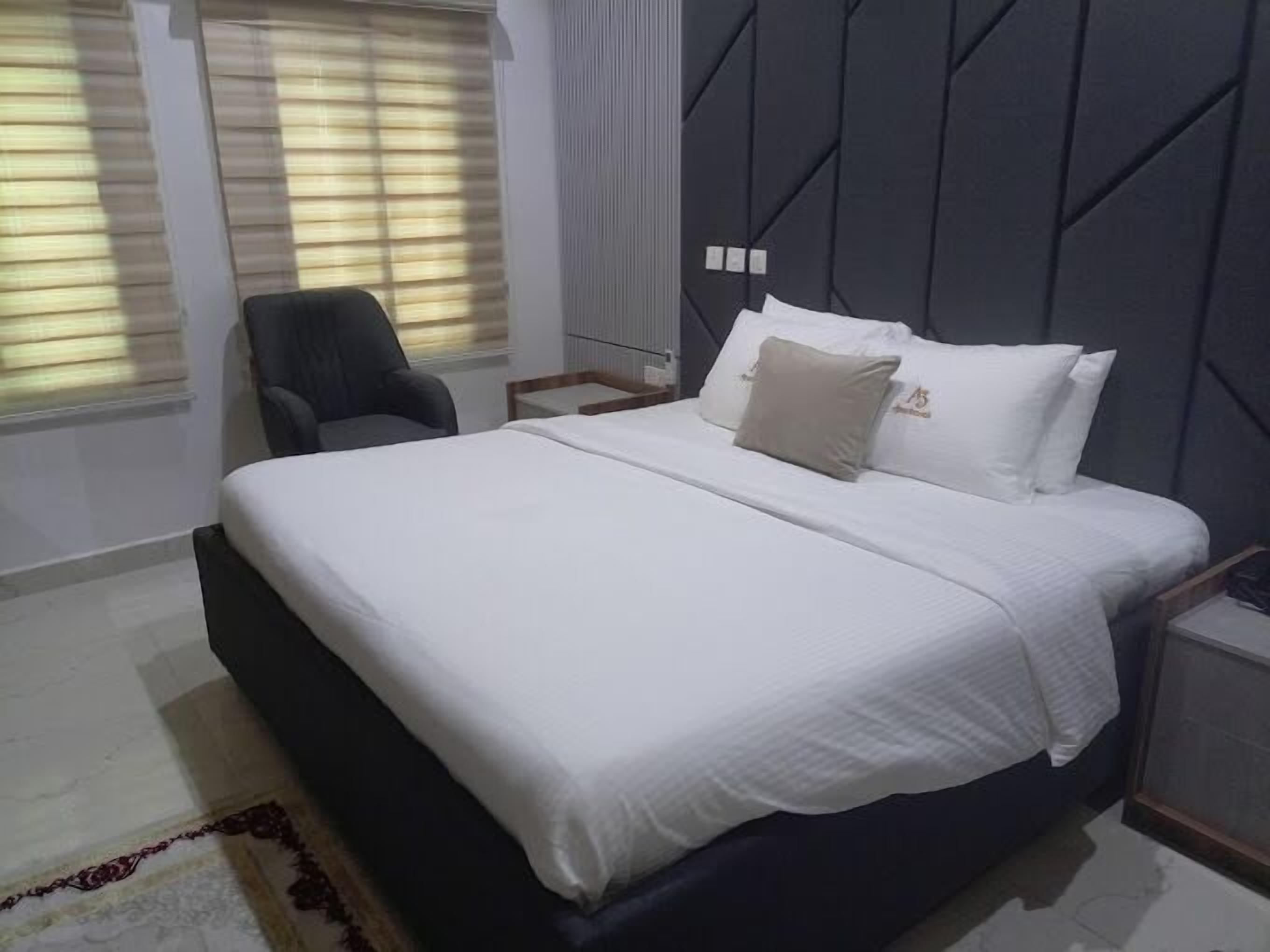 Un dormitorio moderno con una cama grande, una silla y una mesita de noche.