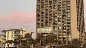 A high-rise hotel with multiple balconies, a beach view, and a sunset sky. - SEPT DEAL 1BR OCEANFRONT KING,pools,hotub,pristine,free parking & stunning views (Myrtle Beach)