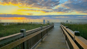 A wooden boardwalk leading to a beach with a sunset in the background. - SEPT DEAL 1BR OCEANFRONT KING,pools,hotub,pristine,free parking & stunning views (Myrtle Beach)